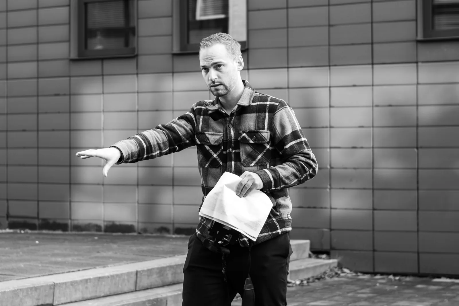Zwart-witfoto van Erwin Eijpe die met uitgestrekte arm een aanwijzing geeft, het script in zijn andere hand